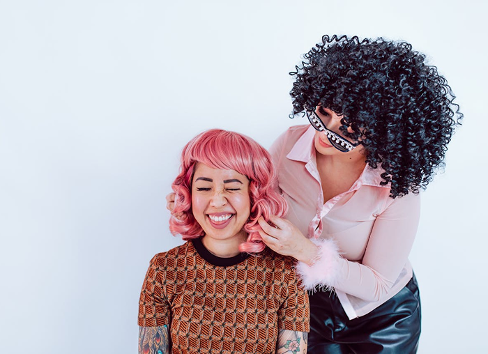 A stylist working with a client wearing a pink wig, showing the hands-on, personalized service experience